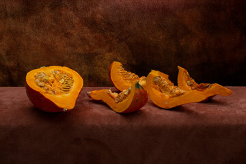 Pieces of cut Hokkaido pumpkin on brown background