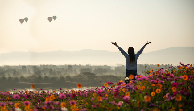 Asian woman relax and freedom in beautiful blooming cosmos flower garden. Travel happy and Lifestyle Concept.