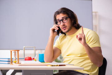 Young male student physicist preparing for exams in the classroo