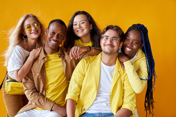 group of happy diverse young men and women isolated on yellow background, five friendly mixed race...