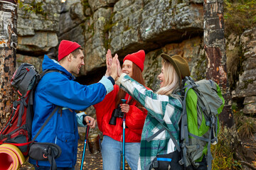 team of sportive friends travelling together, they give high five to each other, happy to hike