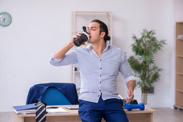 Young handsome male employee doing exercises in the office