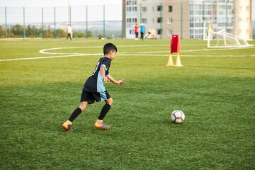 young caucasian school kids playing football in a field, stadium. boys 8-9 years old kicking soccer...