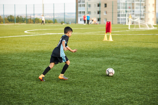 young caucasian school kids playing football in a field, stadium. boys 8-9 years old kicking soccer on the sports grass pitch, wearing sportswear on football match