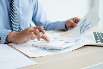 The businessman's hand sits at their desks and calculates financial graphs showing results about their investments, plan a successful business growth process