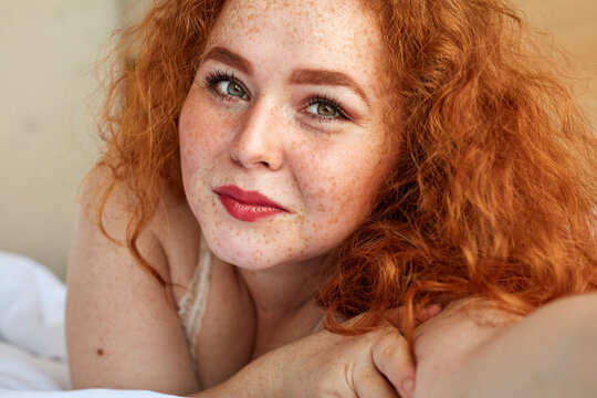 beautiful shy red haired female with nice freckles look at camera, closeup portrait of overweight pretty woman in lingerie