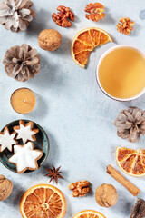 Fototapeta na wymiar Winter holidays background with a place for text. Tea, cinnamon cookies, dried oranges and cute organic decor, top shot with copyspace