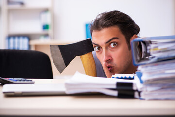 Young employee angry with excessive work holding hatchet