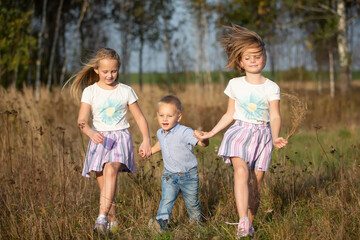 Fototapeta na wymiar Happy family: sisters and little brother on a summer meadow.