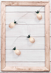 Christmas rustic background with string lights as pineapples golden colored on white wooden. Festive decoration, New Year fairy garland.