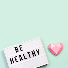 Healthcare and medical concept. Lightbox with words Be Healthy and pink paper heart. Health wishes.