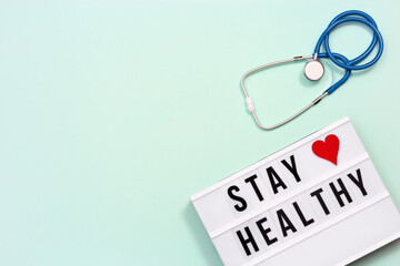 Lightbox with words  Stay Healthy and blue stethoscope. Care of health and medical concept. World health day.
