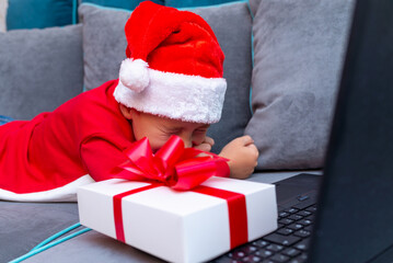 Happy laughing boy meets Christmas through a video call with friends during pandemic coronavirus.