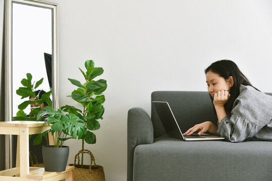 Woman Working From Home By Laptop Computer Surround Green Tropical Tree, Human And Nature, Houseplants Growing In Living Room For Indoor Air Purification And Home Decorative.