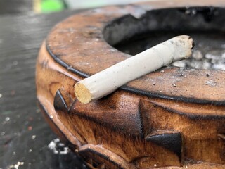 A cigarette butt on the wooden ashtray 