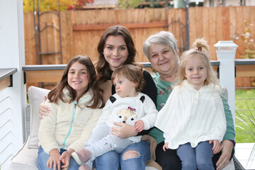 Photo session of the Four Beautiful Sisters sitting on the Porch with Grandmother, Happy Family Concept, Fall Background, November 2020