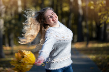 Cheerful woman with fluttering hair in the autumn park.