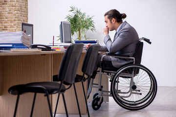 Young male enployee in wheel-chair at workplace