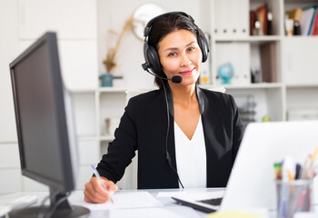 Young asian woman call centre operator with headphones during working in modern office