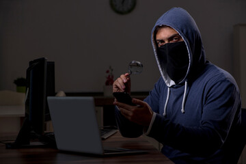 Male hacker hacking security firewall late in office