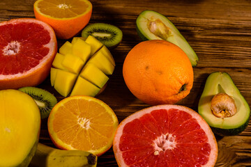 Still life with exotic fruits. Bananas, mango, oranges, avocado, grapefruit and kiwi fruits on wooden table