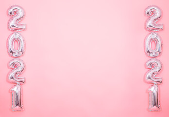 Light pink background with silver balloons in the form of numbers 2021