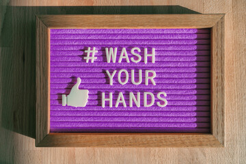 Wash your hands hashtag message on purple billboard notice at business store good hand hygiene for coronavirus prevention. Felt sign for social media against COVID-19.