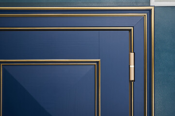 Classic wood entrance door in dark blue with carved panels and gold patina