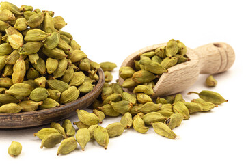 Isolated cardamom seeds in wooden plate and scoop