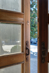 Opened wooden door with dusty glass with blurred street background