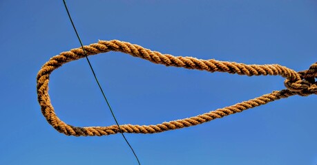 Rope and blue sky background.  A rope tied off as sailor's knot.