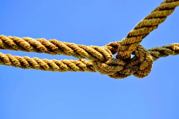 Rope and blue sky background.  A rope tied off as sailor's knot.