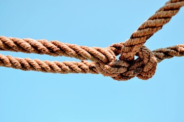 Rope and blue sky background.  A rope tied off as sailor's knot.