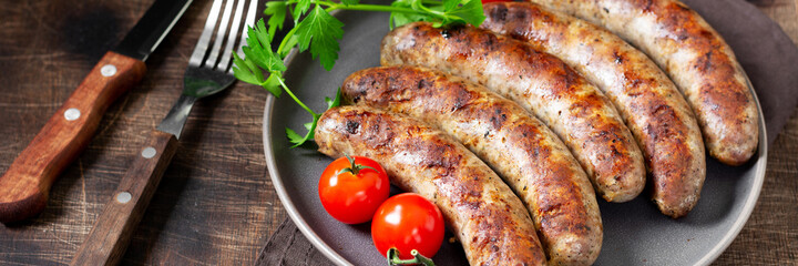 Fried sausages. Grilled sausages with spices, sauce, tomatoes and parsley. Delicious meat sausages...
