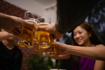 Group of Asian workers cheers to a beer after work. They are in the restaurant at night.