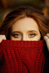 Autumn portrait of a red-haired woman in nature in the light of sunset. Redhead