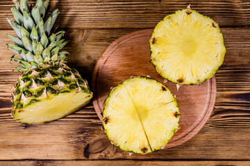 Cutting board with sliced pineapple on wooden table. Top view