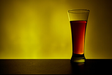 Tall glass of cold tea on warm yellow background. Fresh summer beverage.