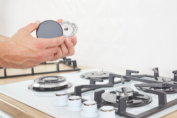 Worker install burner on gas hob in kitchen interior. Repairs of gas control panel.