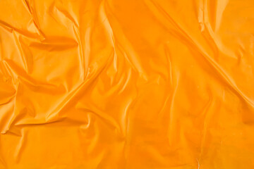Crumpled glossy orange magazine paper poster background.