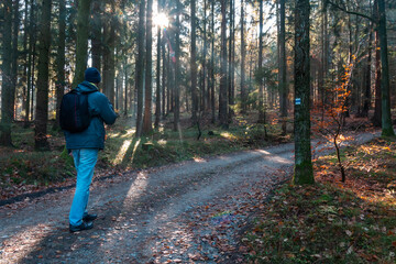 Young man walking on touristic path in misty morning fog forest. Czech landscape