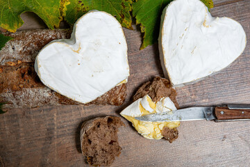 French Neufchatel cheese shaped heart on wooden background