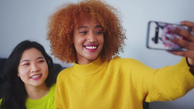 Best friends Asian and african american black woman taking selfie using smartphone. Funny faces. High quality 4k footage