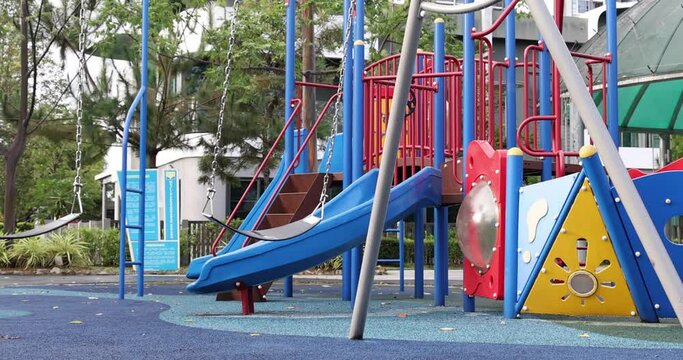 Kuala Lumpur, Malaysia - November 8, 2020: A slow motion footage of an empty, abandoned, swinging swing in a playground. Due to corona pandemic crisis, playgrounds are blocked for use.