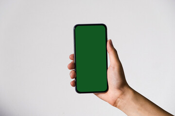 Hand holding white mobile phone with blank mint green screen in white background.