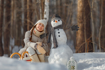 happy child girl plaing with a snowman on a snowy winter walk