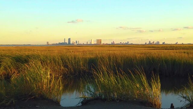 HD 120 fps slight pan left to right of waterway view of Atlantic City skyline with mostly clear sky near golden hour