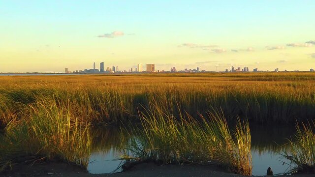 HD 120 fps static waterway view of Atlantic City skyline with mostly clear sky near golden hour