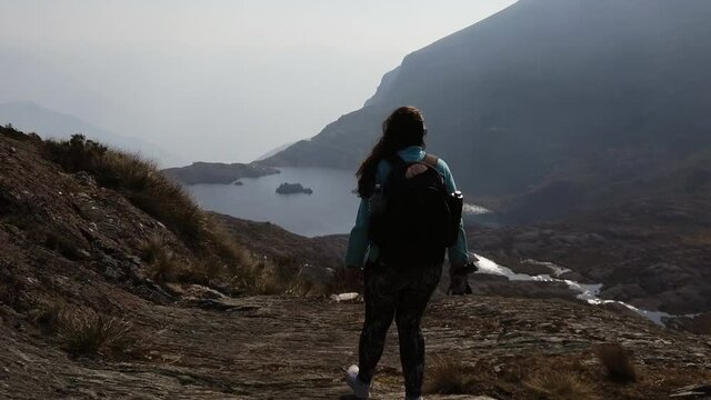 4k daytime video with a girl trekking the beautiful route of the 5 Lakes of Pichgacocha from Ambo,  Huanuco, Peru in the Andes mountains. Dolly in, pointing down and to the right with wide angle shot.