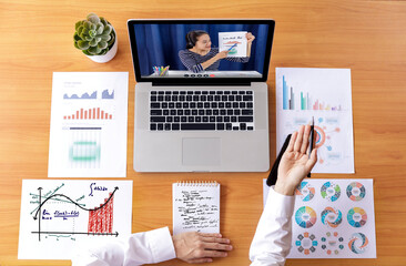 Fototapeta na wymiar Top view Businessman and businesswoman analysis financial chart with videoconference online meeting. Hand of businesswomen using laptop meeting with diverse colleagues. Covid-19 working from home.